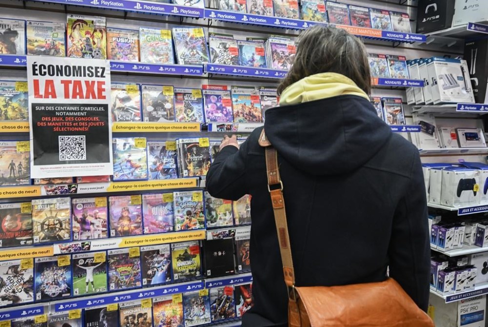 Business groups say the tax holiday is on track to boost sales for retailers and restaurant owners, even though some have struggled to implement the temporary deal. Customers browse products at a Game Stop store next to a sign advertising