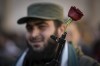 FILE - A Syrian fighter holds a gun with a flower placed in the barrel, as people gather for Friday prayers at the Umayyad mosque in Damascus, Syria, Friday, Dec. 13, 2024. (AP Photo/Leo Correa, File)