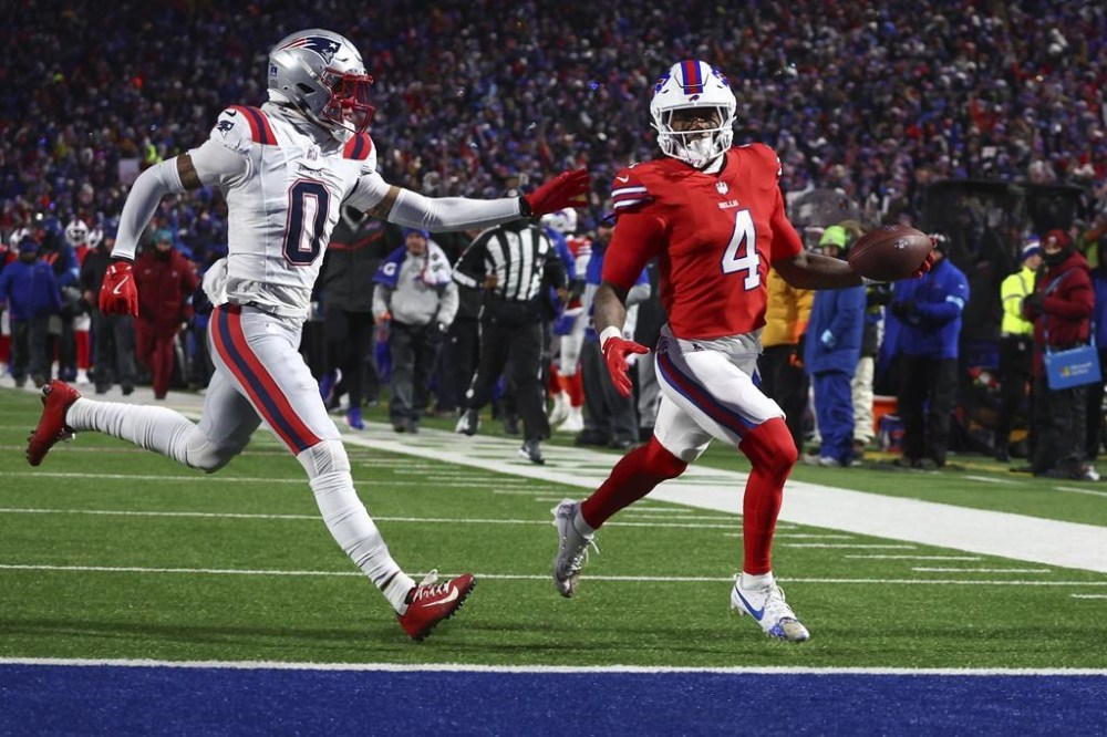 Buffalo Bills running back James Cook (4) carries the ball into the end zone against New England Patriots cornerback Christian Gonzalez (0) for a touchdown against the during the second quarter of an NFL football game, Sunday, Dec. 22, 2024, in Orchard Park, N.Y.. (AP Photo/Jeffrey T. Barnes)