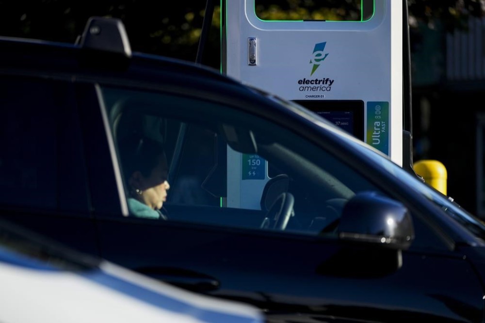 FILE - A driver waits in their car while charging an electric vehicle at an Electrify America station, Oct. 9, 2024, in Seattle. (AP Photo/Lindsey Wasson, File)