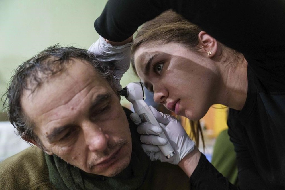 A medic checks the ear of an injured Ukrainian serviceman at Medical Service