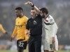 Manchester United's Bruno Fernandes, right, confronts referee Tony Harrington, centre, after being shown a yellow card during the English Premier League soccer match between Wolverhampton Wanderers and Manchester United at the Molineux Stadium, Wolverhampton, England, Thursday, Dec. 26, 2024. (Nick Potts/PA via AP)