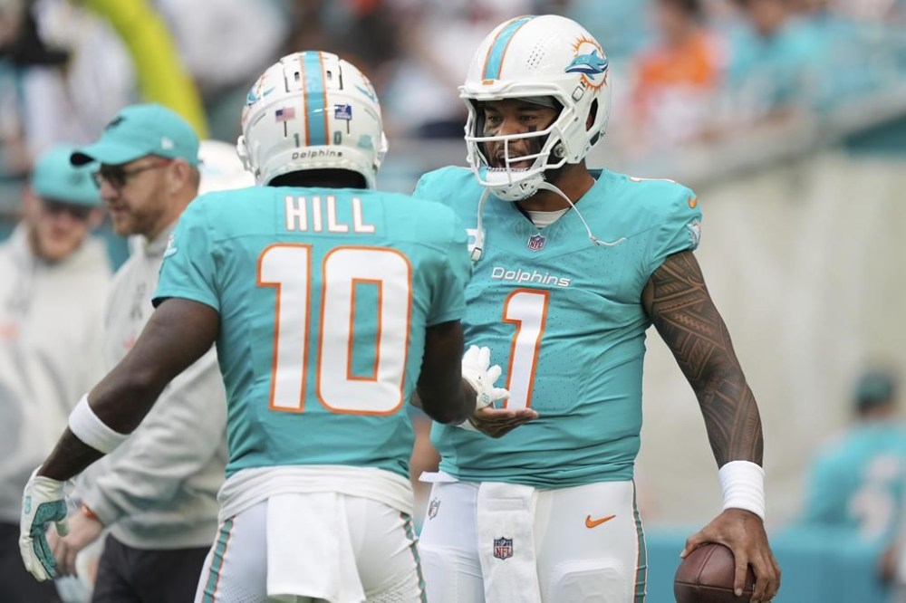 Miami Dolphins quarterback Tua Tagovailoa (1) and wide receiver Tyreek Hill (10) talk on the field before an NFL football game against the San Francisco 49ers, Sunday, Dec. 22, 2024, in Miami Gardens, Fla. (AP Photo/Rebecca Blackwell)