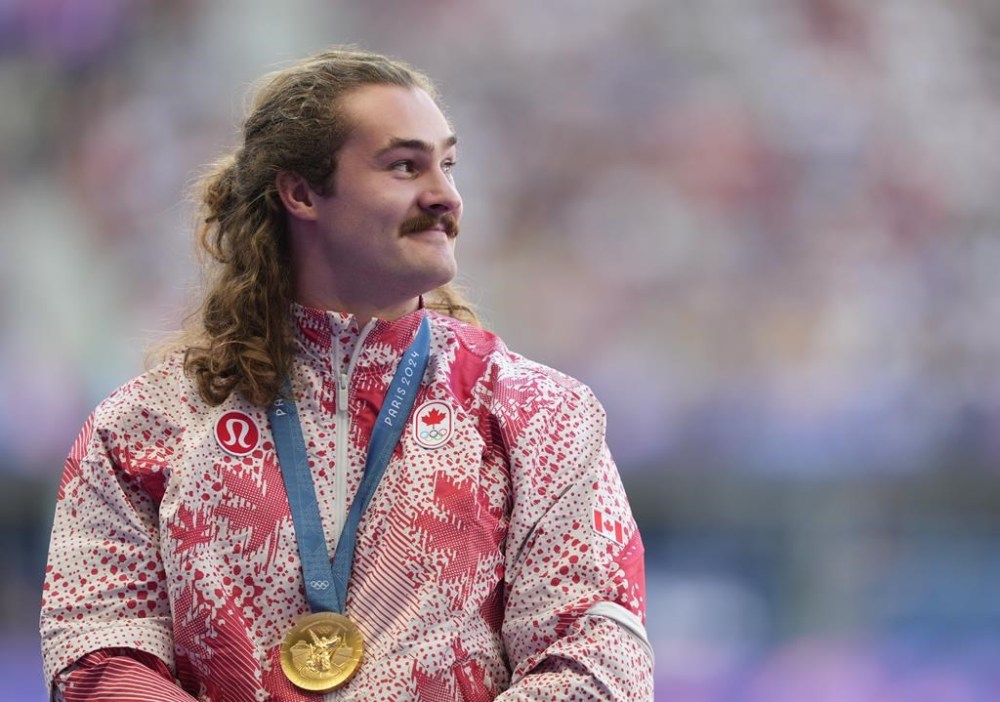 Ethan Katzberg, of Nanaimo, B.C., receives his gold medal in the men's hammer throw event at the 2024 Summer Olympics, in Saint-Denis, France, Monday, Aug. 5, 2024. THE CANADIAN PRESS/Christinne Muschi