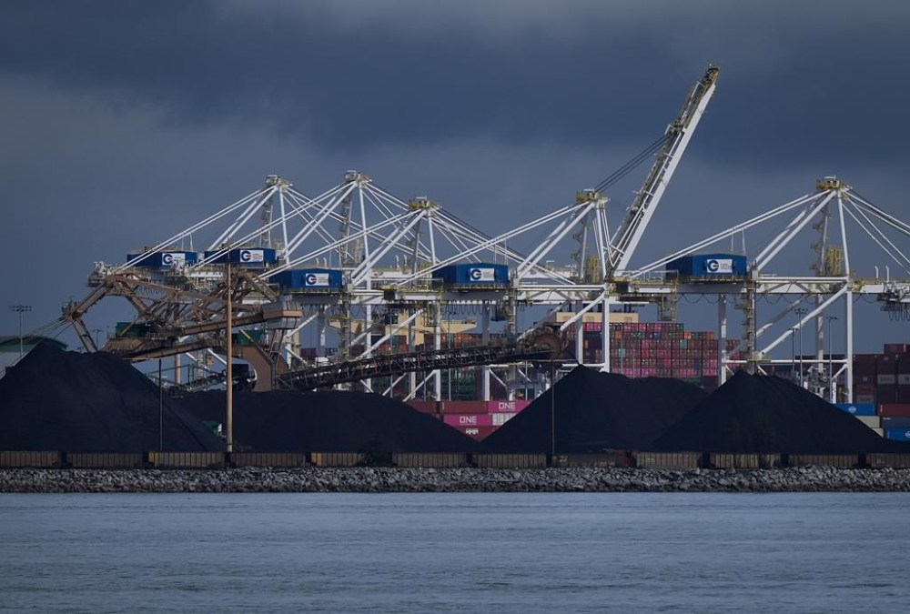 Piles of coal at the Westshore coal export terminal at Roberts Bank and gantry cranes used to load and unload containers onto and from cargo ships are seen at Deltaport, in Tsawwassen, B.C., on Monday, September 9, 2024. THE CANADIAN PRESS/Darryl Dyck