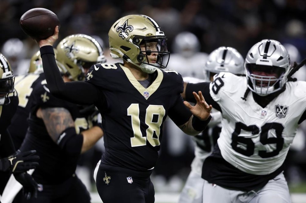 New Orleans Saints quarterback Spencer Rattler (18) throws a pass as he is pressured by Las Vegas Raiders defensive tackle Adam Butler (69) during the first half of an NFL football game, Sunday, Dec. 29, 2024, in New Orleans. (AP Photo/Butch Dill)