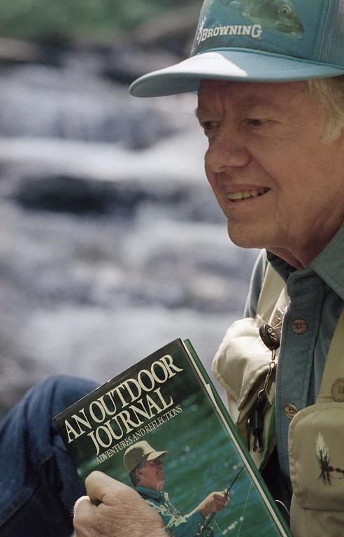 FILE - Former President Jimmy Carter holds a copy of his book,