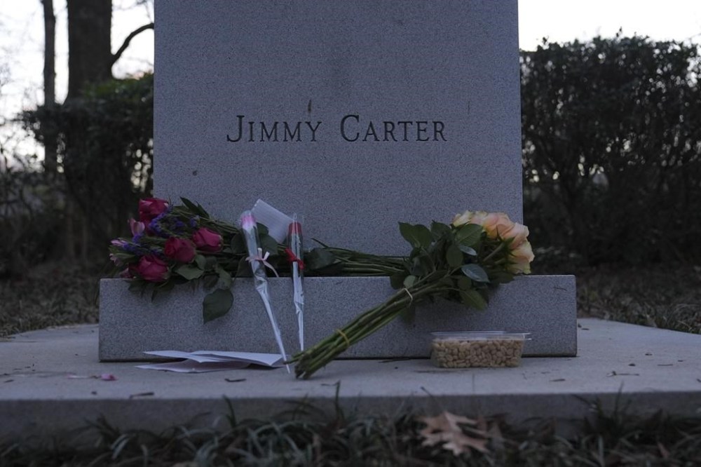 Bouquets of flowers and peanuts rests at the base of a bust of former President Jimmy Carter at the Jimmy Carter Presidential Library and Museum on Sunday, Dec. 29, 2024, in Atlanta. (AP Photo/Brynn Anderson)