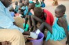 FILE - In this Nov. 4, 2010 photo, Ajak Kuol Nyamchiek, 7, watches while John Lotiki, a nurse with the Carter Center, bandages the blister on her leg from where a guinea worm is slowly emerging in Abuyong, Sudan. (AP Photo/Maggie Fick, File)