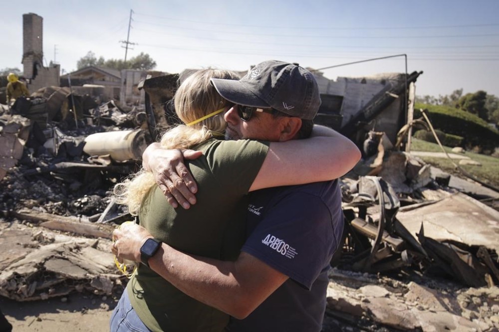 FILE - Kelly Barton, left, is hugged by a family friend after arriving at her parents' fire-ravaged property in the aftermath of the Mountain Fire, Nov. 7, 2024, in Camarillo, Calif. (AP Photo/Ethan Swope, File)