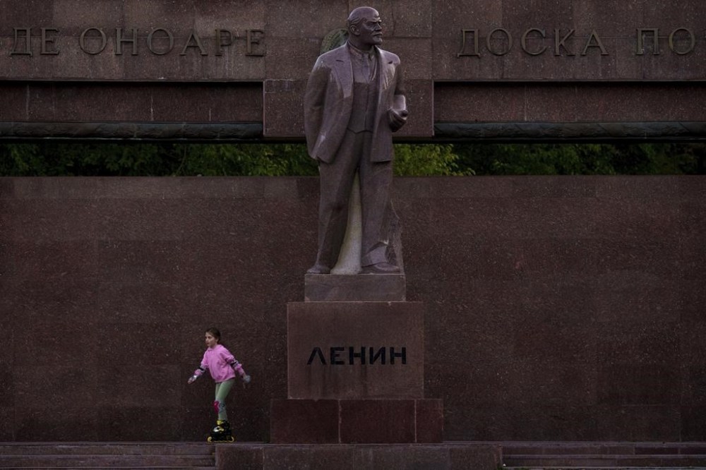 FILE - A girl skates next to a statue of Lenin, with the words
