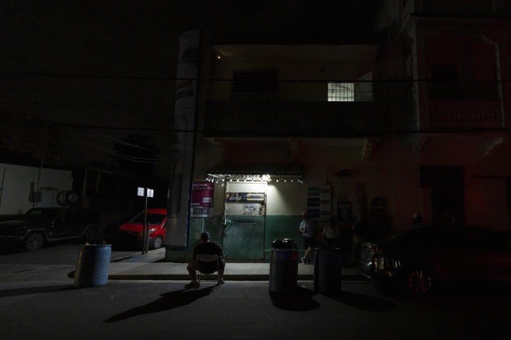 A lamp powered by a generator illuminates a sidewalk during a blackout in San Juan, Puerto Rico, after sunset Tuesday, Dec. 31, 2024. (AP Photo/Alejandro Granadillo)