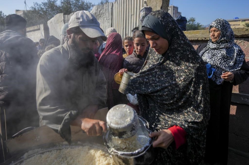 Palestinians collect donated food at a food distribution center in Deir al-Balah, central Gaza Strip, Thursday Jan. 2, 2025. (AP Photo/Abdel Kareem Hana)
