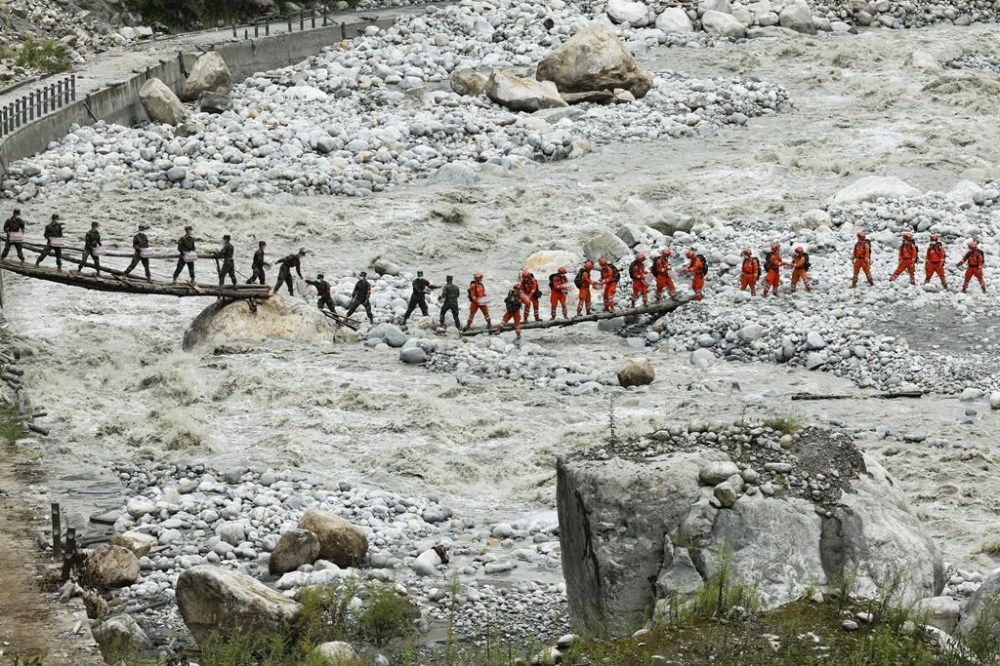 FILE -In this photo released by Xinhua News Agency, rescuers deliver supplies via a temporary bridge in the aftermath of an earthquake near Moxi Town of Luding County, southwest China's Sichuan Province, Sept. 8, 2022. (Shen Bohan/Xinhua via AP, File)
