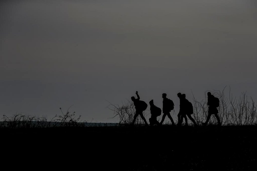 FILE - Migrants walk to enter Greece from Turkey by crossing the Maritsa river (Evros river in Greek) near the Pazarkule border gate in Edirne, Turkey, March 1, 2020. (AP Photo/Emrah Gurel, File)