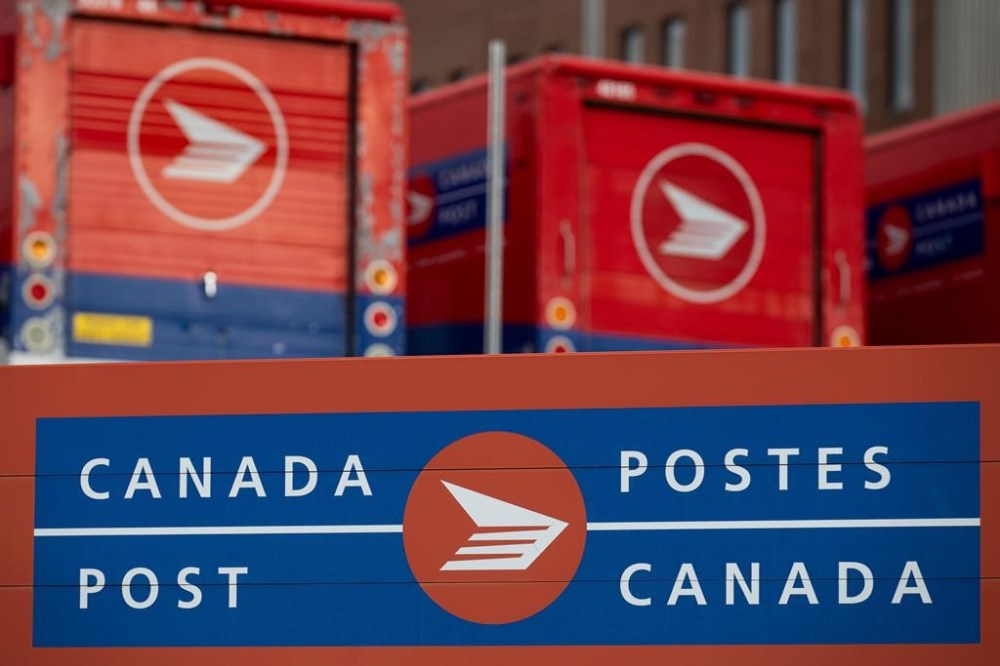 Canada Post says it has reinstated on-time service guarantees and returned to full service levels for domestic parcels after a strike brought deliveries to a halt last year. Canada Post signage and parked vehicles are seen at a Canada Post mail sorting facility during a nationwide strike action in Ottawa, on Monday, Nov. 18, 2024. THE CANADIAN PRESS/Spencer Colby