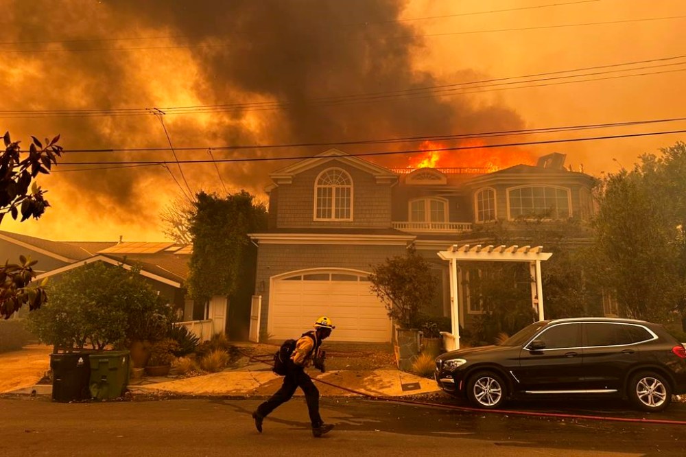 A residence burns as a firefighter battles the Palisades Fire in the Pacific Palisades neighborhood of Los Angeles Tuesday, Jan. 7, 2025. (AP Photo/Eugene Garcia)