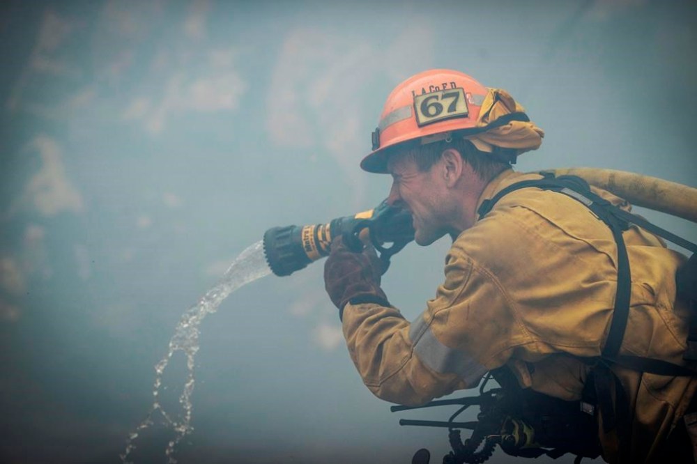 A firefighters make a stand in front of the advancing Palisades Fire in the Pacific Palisades neighborhood of Los Angeles, Tuesday, Jan. 7, 2025. (AP Photo/Ethan Swope)