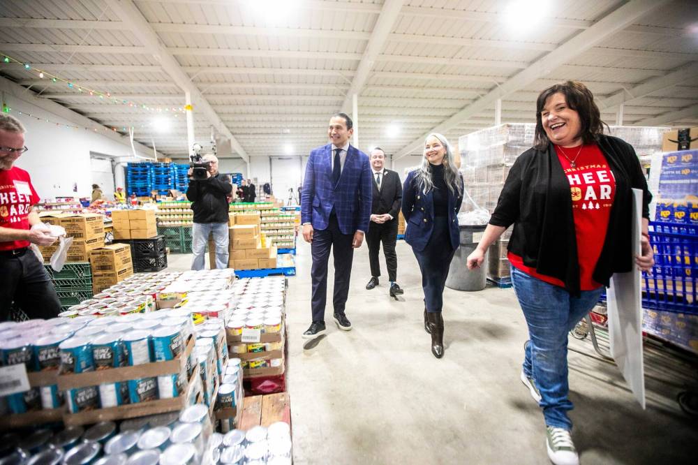 MIKAELA MACKENZIE / FREE PRESS
Premier Wab Kinew (left), families minister Nahanni Fontaine, and Christmas Cheer Board executive director Shawna Bell tour the organization after the government of Manitoba gave a cheque for one hundred thousand dollars to the cheer board on Friday.