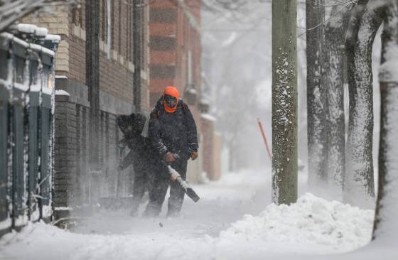 People clear snow on a sidewalk along Westminster Avenue Sunday. (John Woods / Free Press)