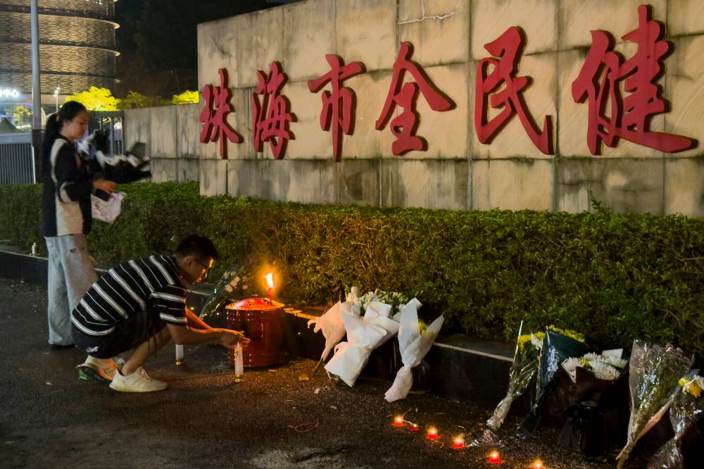 NG HAN GUAN / THE ASSOCIATED PRESS FILES
A man lights a candle outside the ‘Zhuhai People’s Fitness Plaza’ where a man deliberately rammed his car into people exercising at the sports centre, killing some and injuring others in Zhuhai on Nov. 12. Social unrest is growing in China.