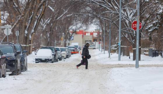 Pedestrians navigate the snow-covered street along Westminster Avenue Tuesday afternoon. (Mike Deal / Free Press)