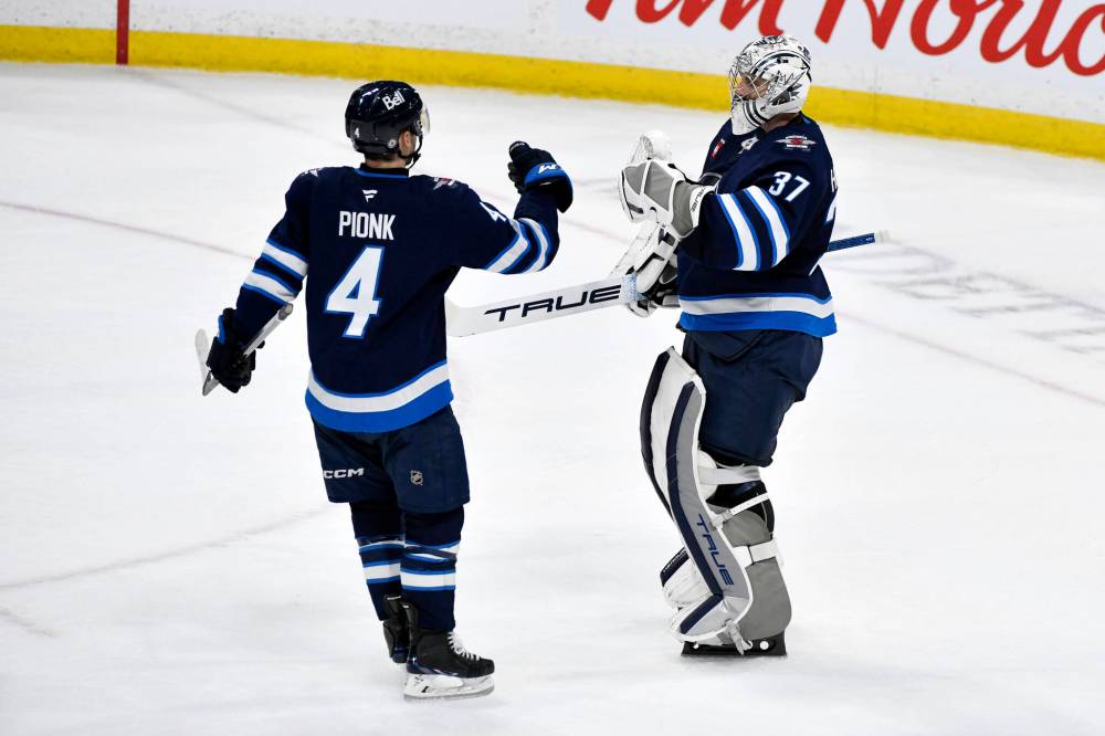 FRED GREENSLADE / THE CANADIAN PRESS
Jets’ goaltender Connor Hellebuyck celebrates regular-season victory number 299 and his fifth shutout of the season Monday night with blue-liner Neal Pionk.