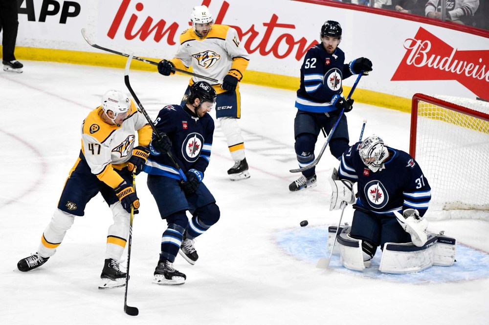 FRED GREENSLADE / THE CANADIAN PRESS
Connor Hellebuyck makes a save on a shot by Nashville Predators' Michael McCarron as he is defended by Colin Miller during the first period of game in Winnipeg.
