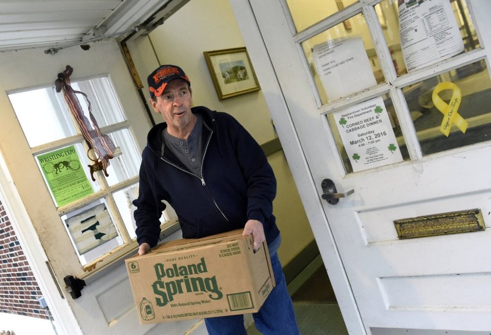 Town Judge Richard Snyder carries bottled water from a distribution center on Feb. 20, 2016, at the Petersburgh Town Hall in Petersburgh, N.Y. (Cindy Schultz/The Albany Times Union via AP)