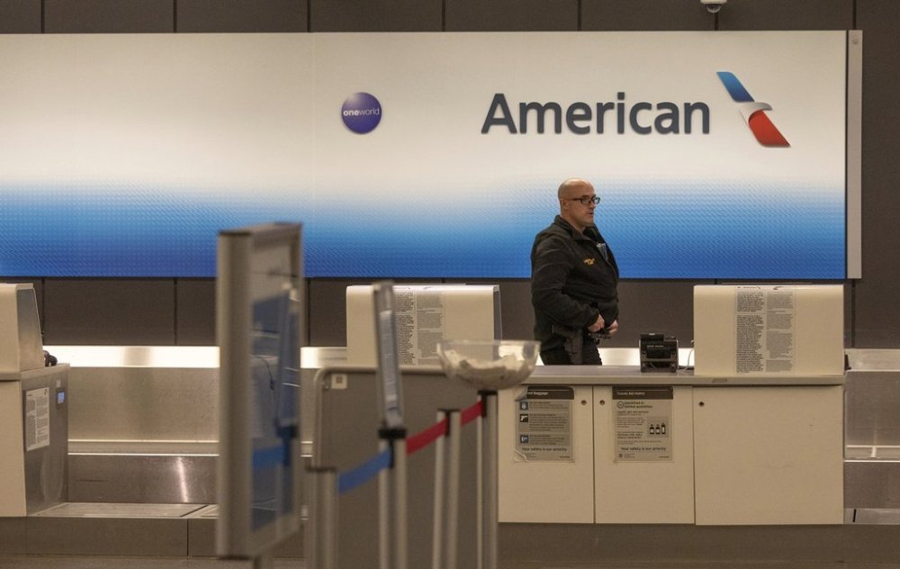 An airport police officer walks behind the American Airlines counter at Wichita's Eisenhower Airport, Wednesday, Jan. 29, 2024, in Wichita, Kan., after news that an American Airlines flight from Wichita collided with a helicopter near Ronald Reagan Washington Airport. (AP Photo/Travis Heying)