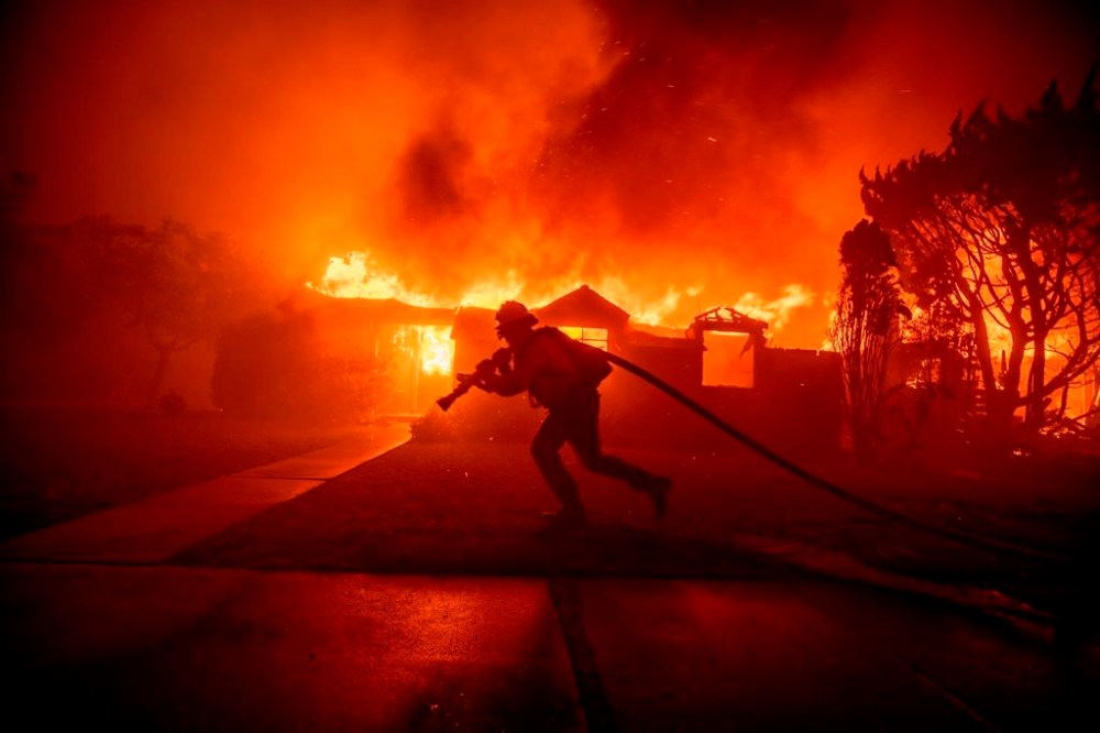 A firefighter battles the Palisades Fire as it burns a structure in the Pacific Palisades neighborhood of Los Angeles, Tuesday, Jan. 7, 2025. (AP Photo/Ethan Swope)