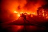 A firefighter battles the Palisades Fire as it burns a structure in the Pacific Palisades neighbourhood of Los Angeles, Tuesday, Jan. 7, 2025. THE CANADIAN PRESS/AP-Ethan Swope