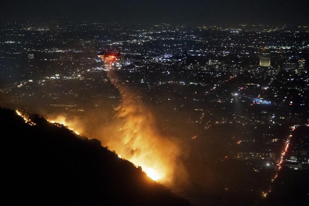 Water is dropped by helicopter on the burning Sunset Fire in the Hollywood Hills section of Los Angeles, Wednesday, Jan. 8, 2025. (AP Photo/Ethan Swope)