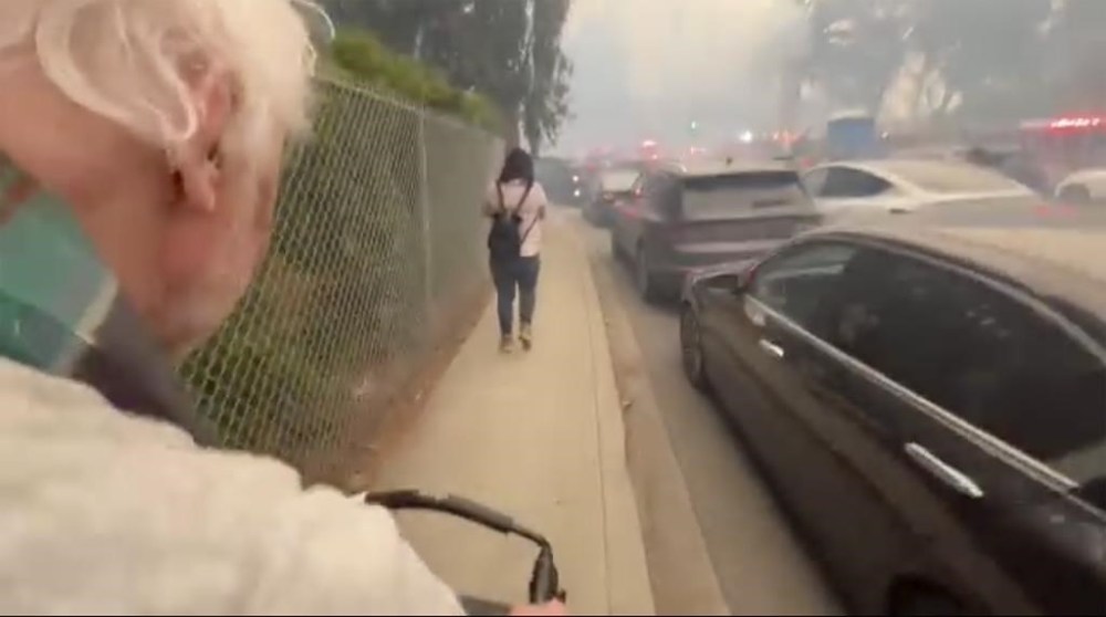 CORRECTS LOCATION TO PACIFIC PALISADES, INSTEAD OF GLENHAVEN - This image taken from video provided by Aaron Samson shows his 83-year-old father-in-law escaping the wildfires after they evacuated a vehicle near Pacific Palisades, Calif., on Tuesday, Jan. 7, 2025. (Aaron Samson via AP)