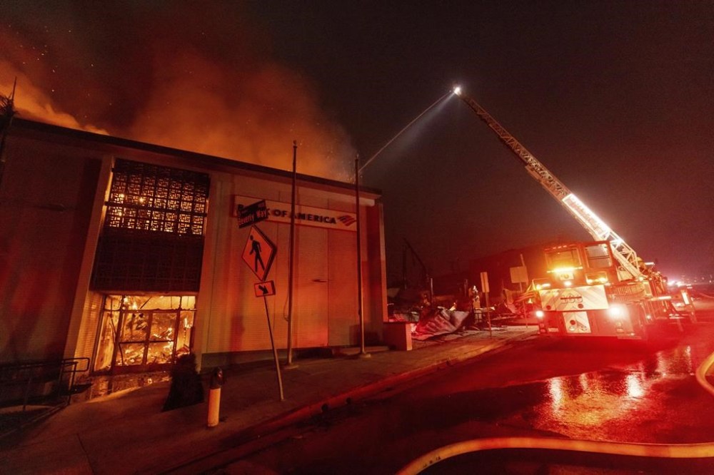 The Eaton Fire burns a Bank Of America branch Wednesday, Jan. 8, 2025 in Altadena, Calif. (AP Photo/Ethan Swope)