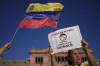 An opponent of Venezuelan President Nicolas Maduro holds a banner that reads in Spanish, 