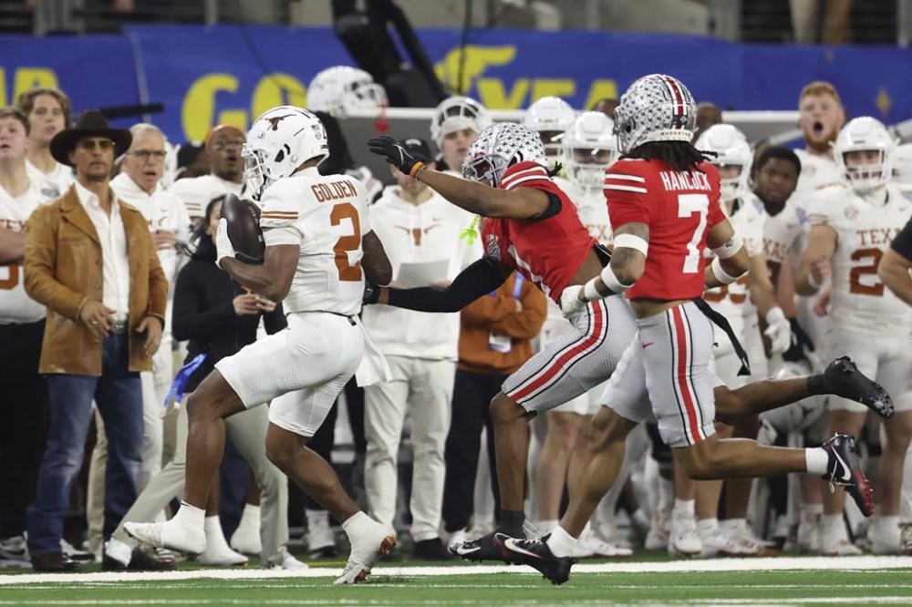 Actor Matthew McConaughey, left, watches as Texas wide receiver Matthew Golden (2) runs toward the sideline against Ohio State cornerback Davison Igbinosun, middle, and cornerback Jordan Hancock (7) during the first half of the Cotton Bowl College Football Playoff semifinal game, Friday, Jan. 10, 2025, in Arlington, Texas. (AP Photo/Gareth Patterson)