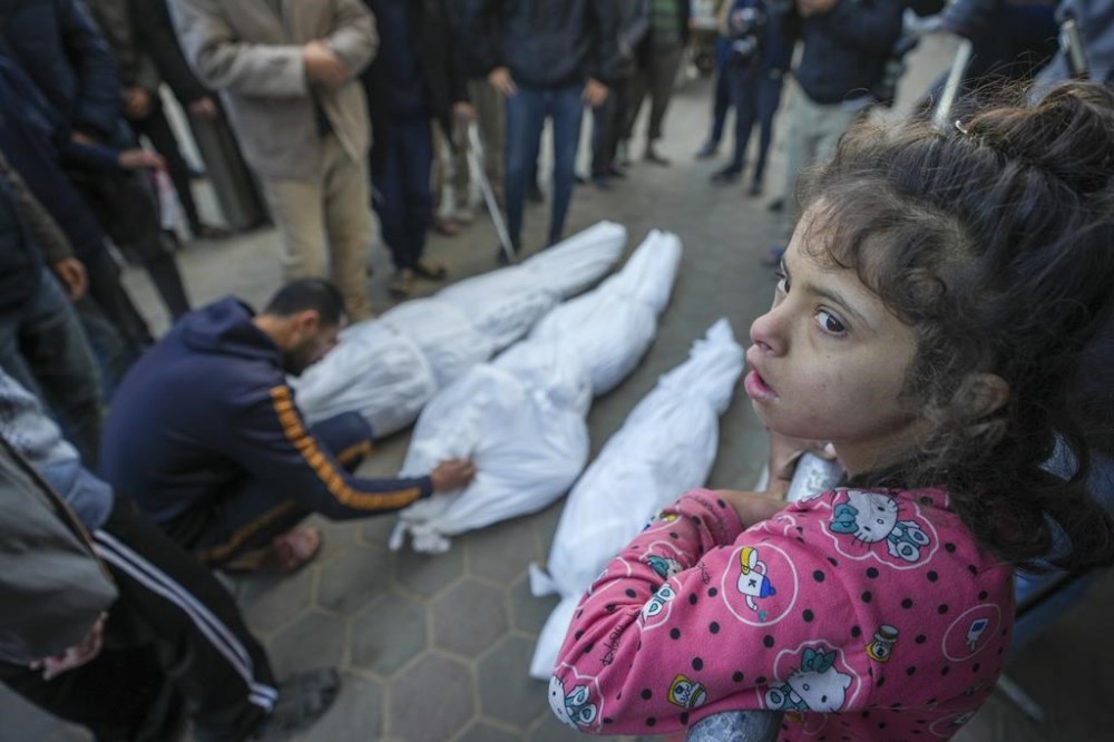 A girl watches as Mohammad Eid mourns his cousin Dima, along with her uncle and grandfather, who were killed in an Israeli airstrike on Saturday, during their funeral in Deir al-Balah, central Gaza Strip, Sunday, Jan. 12, 2025. (AP Photo/Abdel Kareem Hana)