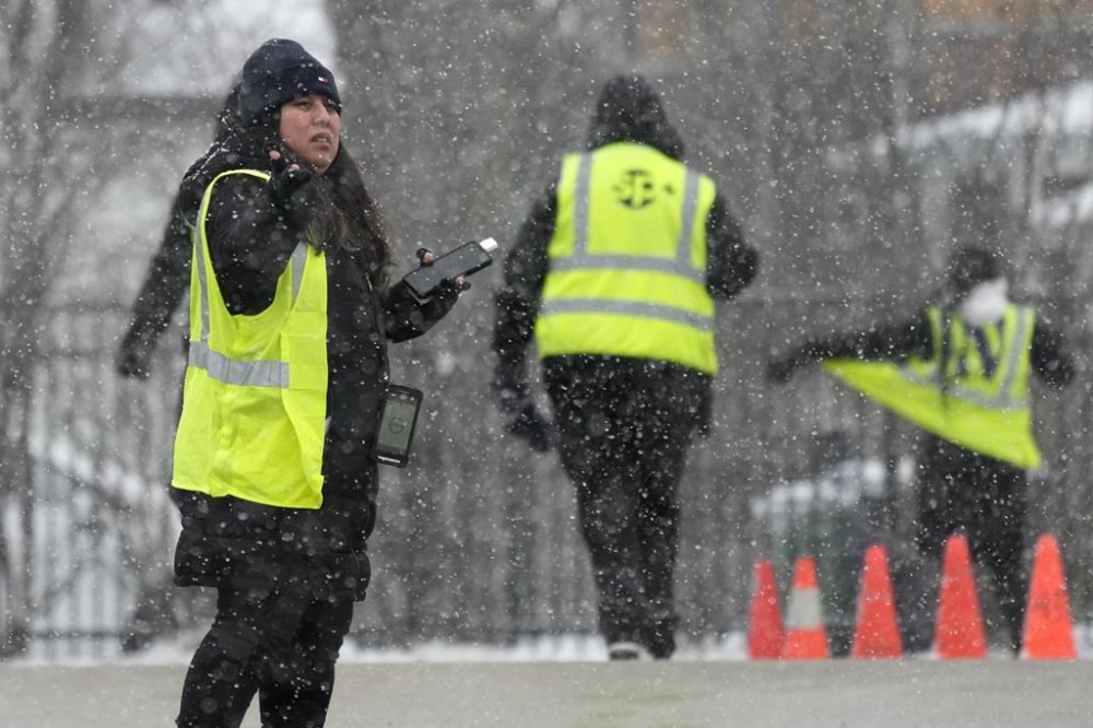 Parking attendants wait to help drivers at a Northwestern University parking lot during a snow day in Evanston, Ill., Sunday, Jan. 12, 2025. (AP Photo/Nam Y. Huh)