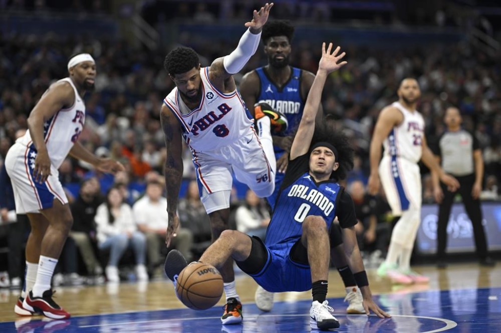 Philadelphia 76ers forward Paul George (8) fouls Orlando Magic guard Anthony Black (0) during the second half of an NBA basketball game, Sunday, Jan. 12, 2025, in Orlando, Fla. (AP Photo/Phelan M. Ebenhack)