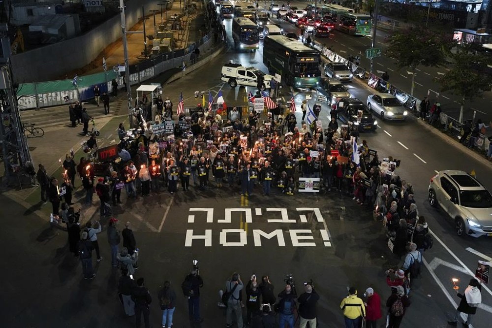 Demonstrators hold torches during a protest calling for the immediate release of the hostages held in the Gaza Strip by the Hamas militant group in Tel Aviv, Israel, on Monday, Jan. 13, 2025. (AP Photo/Ohad Zwigenberg)