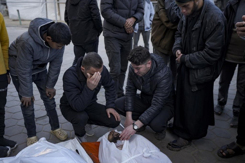 Relatives react next to the body of a Palestinian who was killed in the Israeli bombardment of the Gaza Strip at Al-Aqsa Hospital in Deir Al-Balah, Tuesday, Jan. 14, 2025. (AP Photo/Abdel Kareem Hana)