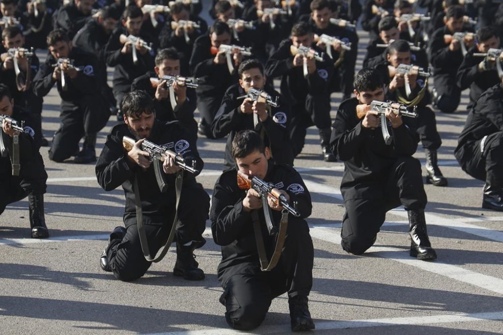Recruits for the new government's police force hold their weapons in a firing position during a training and graduation session at the Police College in Damascus, Syria, Tuesday Jan. 14, 2025.(AP Photo/Omar Albam)