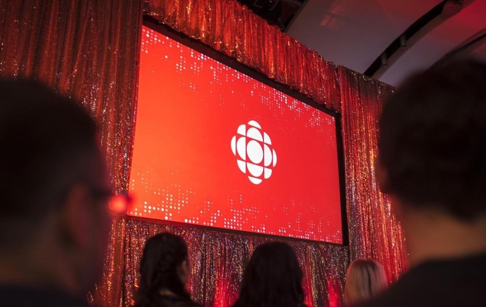 The CBC logo is projected onto a screen during the CBC's annual upfront presentation in Toronto, May 29, 2019. CBC News is planning to boost coverage in nearly two dozen underserved communities across Canada by hiring up to 30 permanent journalists.THE CANADIAN PRESS/Tijana Martin