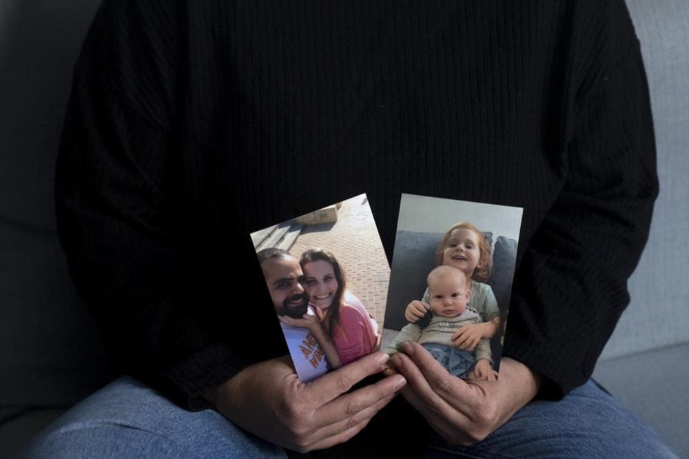 Yifat Zailer shows photos of her cousin, Shiri Bibas, center, her husband Yarden, left, and their sons Ariel, top right, and Kfir, who were taken hostage by Hamas militants, at her home in Herziliyya, Israel, Wednesday, Jan. 15, 2025. (AP Photo/Maya Alleruzzo)