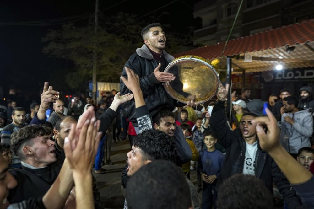 Palestinians celebrate the announcement of a ceasefire deal between Hamas and Israel in Deir al-Balah, central Gaza Strip, Wednesday, Jan. 15, 2025. (AP Photo/Abdel Kareem Hana)