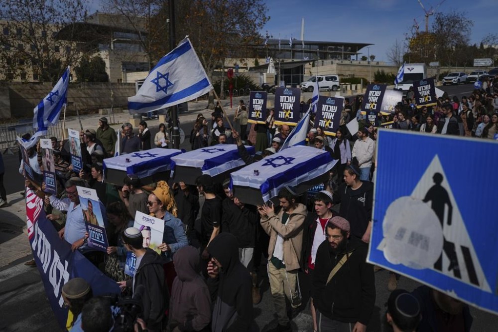 Activists representing families of Israelis killed during the war in Gaza carry mock coffins covered with Israeli flags that are meant to symbolize the price Israel will pay for agreeing to a ceasefire with Hamas in a demonstration against the deal , in Jerusalem on Thursday, Jan. 16, 2025. (AP Photo/Ohad Zwigenberg)
