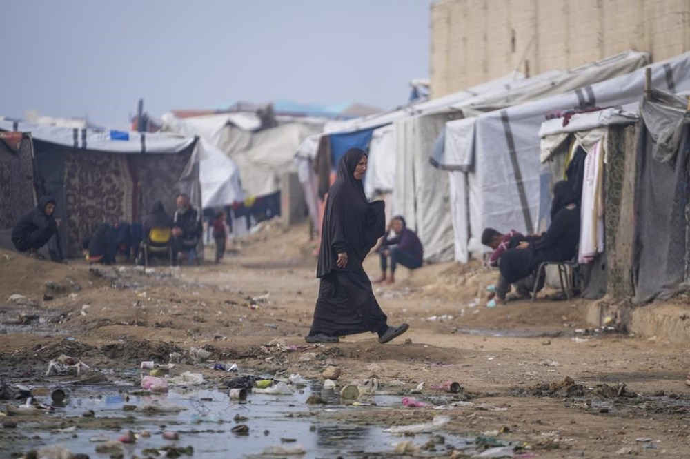 A woman walk at a tent camp for displaced Palestinians in Deir al-Balah, central Gaza Strip, Thursday Jan. 16, 2025. (AP Photo/Abdel Kareem Hana)