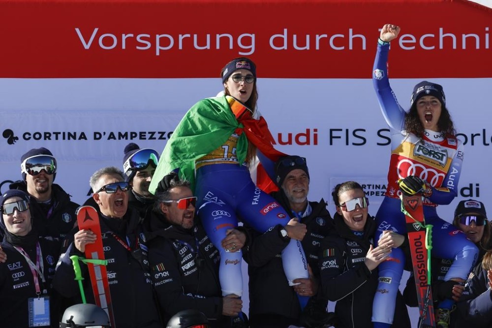 Italy's Sofia Goggia, center, winner of an alpine ski, women's World Cup downhill, and Italy's Federica Brignone, third placed, celebrate with the team at the finish area of an alpine ski, women's World Cup downhill, in Cortina d'Ampezzo, Italy, Saturday, Jan. 18, 2025 (AP Photo/Alessandro Trovati)
