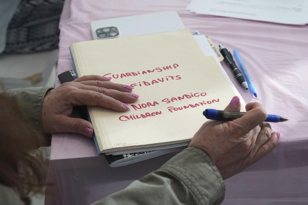 Nora Sandigo holds a folder with documents signed by families giving her legal guardianship of their children, Sunday, Jan. 19, 2025, in Miami. Since December, Sandigo has become the legal guardian of at least 30 children. She has been doing so for 15 years and is the legal guardian to more than 2,000 children. (AP Photo/Marta Lavandier)